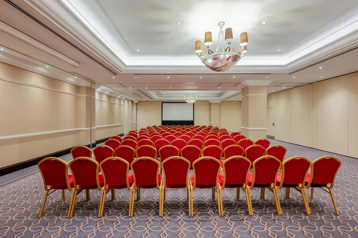 Corinthia Budapest konferenciaterem, elegáns design, piros székek, projektor, 80-100 fő, széksoros elrendezés