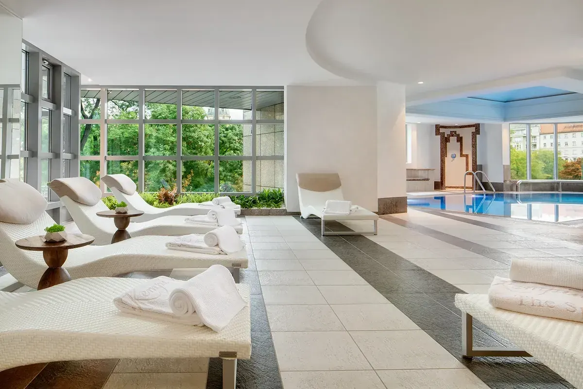 Wellness spa pihenőzóna úszómedencével és fehér napozóágyakkal